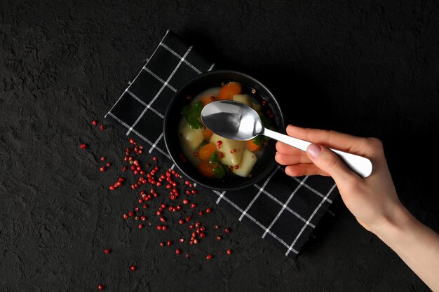 Ręka trzymająca łyżkę nad garnkiem